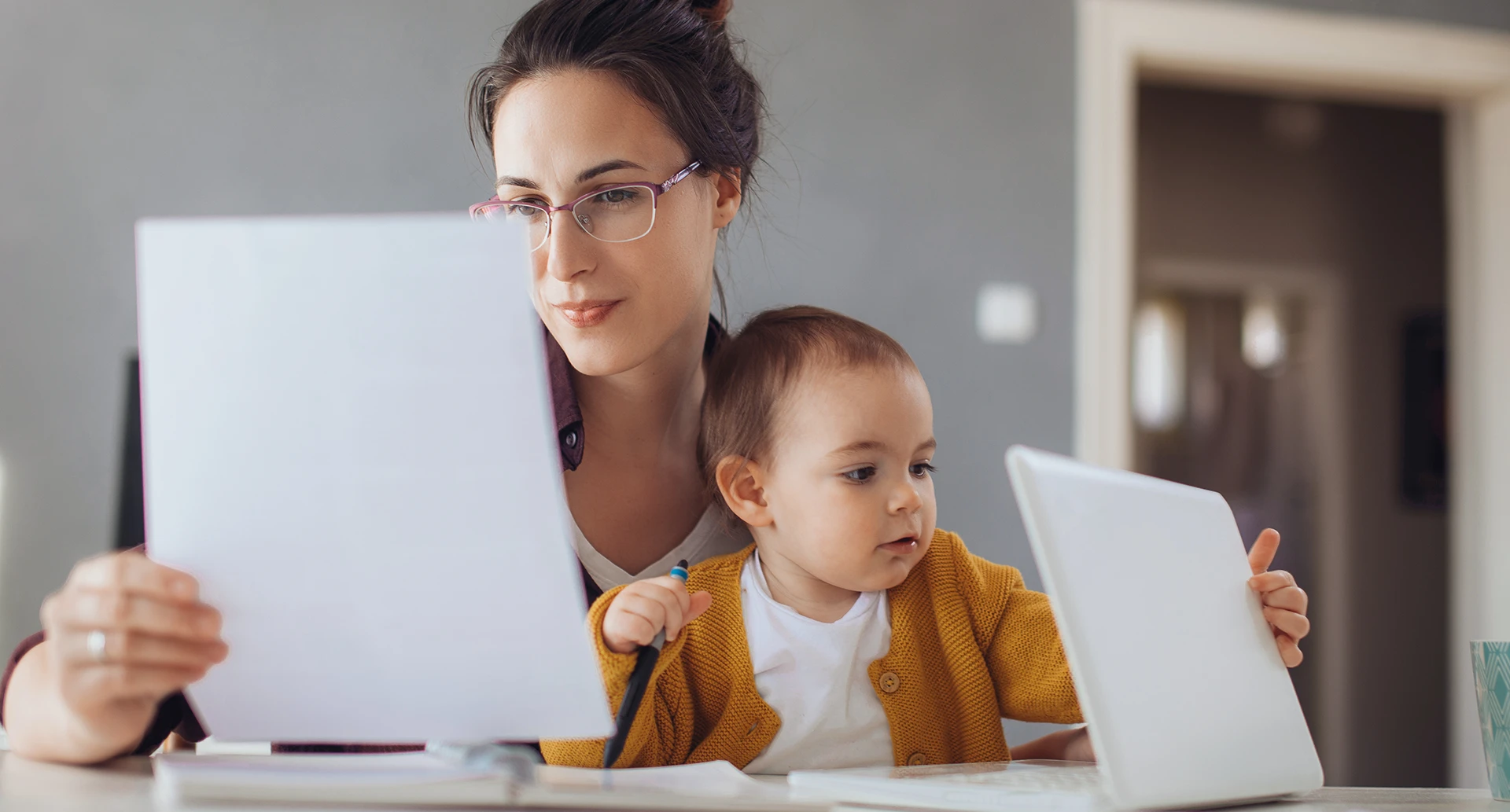 mother holding a document while a baby is sitting on her lap