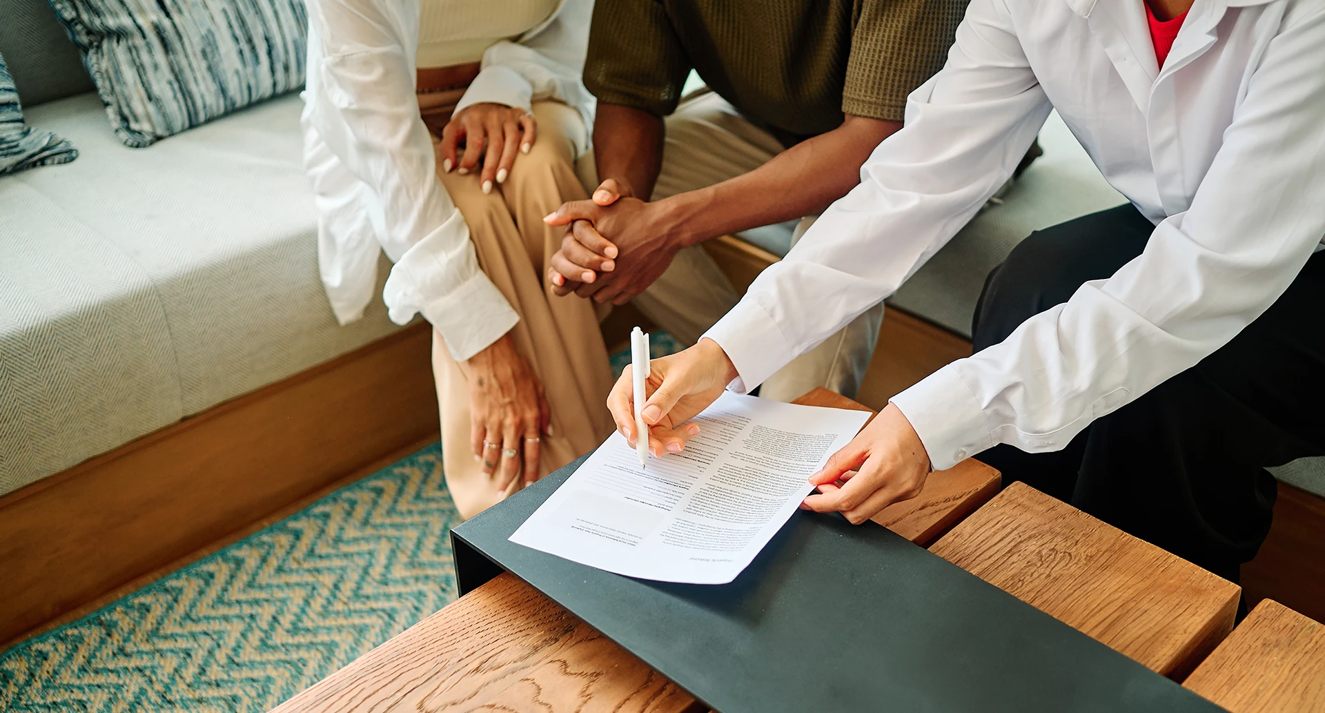 lawyer holding a pen to paper showing a couple where to sign